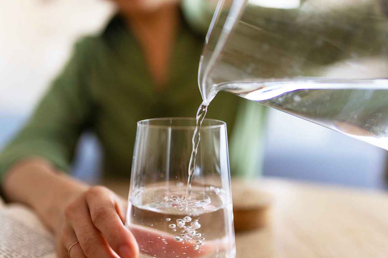 Close Up of Woman Pouring Water From Jug Into Glass